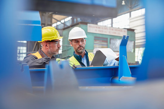 Male foreman and worker reviewing paperwork in factory