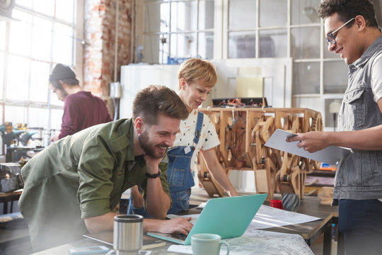 Designers brainstorming at laptop in workshop