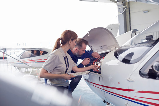 Engineer mechanics working on airplane engine in hangar