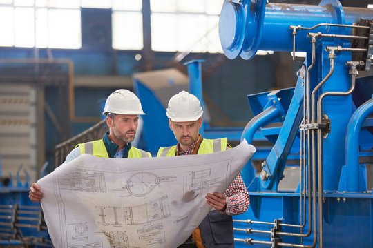 Engineers reviewing blueprints in factory