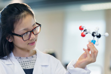 Curious girl student examining molecular structure in classroom