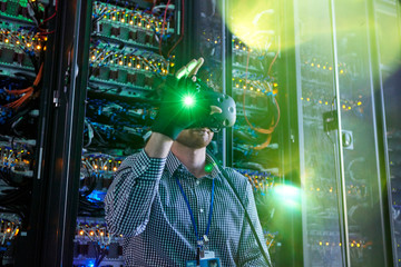 Male computer programmer using virtual reality simulator glasses glowing glove in server room