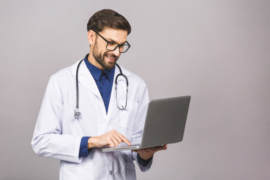 Concentrated Male Doctor Using Laptop Isolated Over Grey Background.