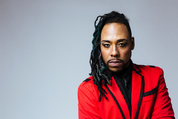 Fototapeta premium Closeup studio portrait of a man wearing a red jacket suit and dreadlocks