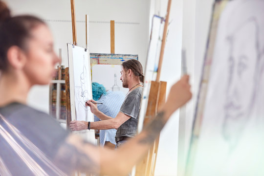 Artists sketching at easels in art class studio
