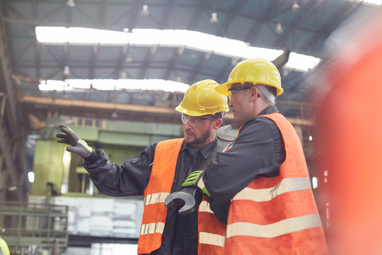Male workers talking in factory