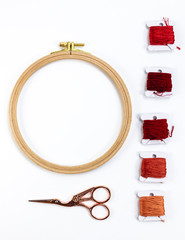 Embroidery accessories. Multicolored bundles of thread, scissors, sewing needles. White background ready for copywriting.