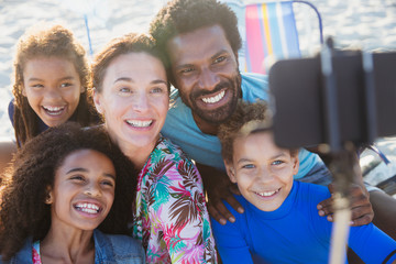 Smiling, happy multi-ethnic family taking selfie selfie stick camera phone on beach