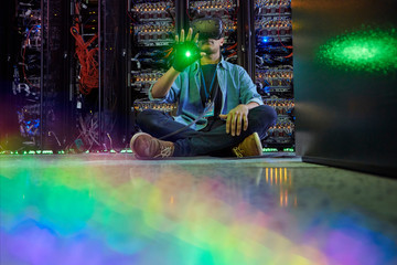 Male computer programmer using virtual reality simulator glasses in dark server room