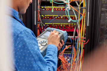 IT technician using fiber optic tester equipment in server room