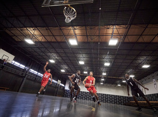 Young male basketball players playing basketball on court in gym