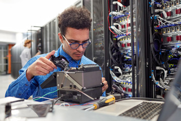 Male IT technician fixing equipment in server room