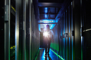 Male security guard with flashlight walking in dark server room
