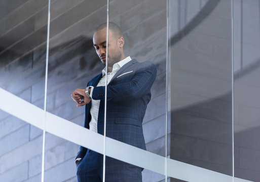 Businessman checking wristwatch at modern office window