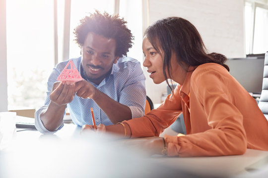 Design professionals examining triangle prototype in office - Powered by Adobe