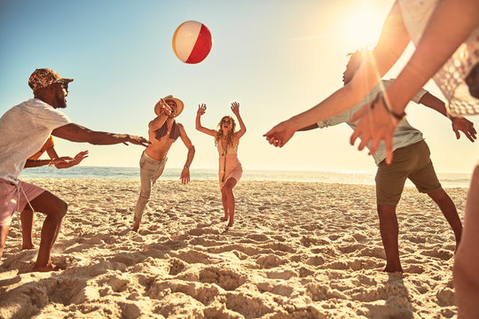 Playful young friends playing with beach ball on sunny summer beach
