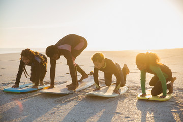 Father surfer teaching children surfing on surfboard on sunny summer beach
