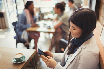 Young woman headphones texting cell phone drinking coffee at cafe table
