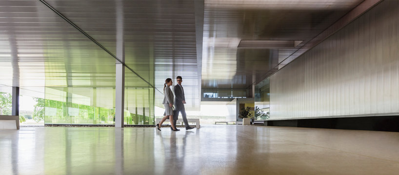Businessman and businesswoman walking in modern office lobby
