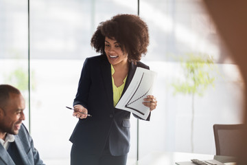 Smiling businesswoman with paperwork leading meeting