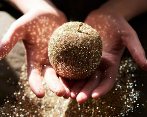 Hands cupping golden glitter apple