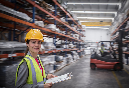Portrait confident, smiling female worker with clipboard in warehouse