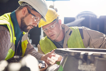 Steelworkers examining steel part in steel mill