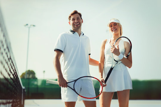 Portrait smiling, confident tennis players holding tennis rackets on sunny tennis court