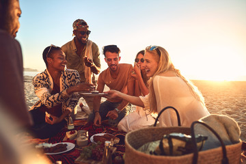 Smiling young friends enjoying picnic on sunny summer beach