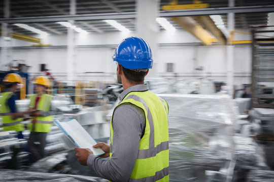 Male supervisor with paperwork walking in steel factory