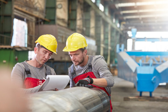 Male workers with clipboard in factory