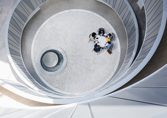 View from above business people meeting at table in round modern atrium courtyard