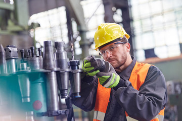 Male worker examining steel parts in factory