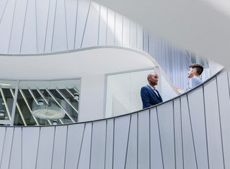 Businessmen talking on architectural, modern office balcony