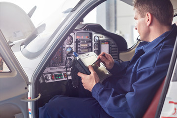 Male engineer checking diagnostics digital tablet in airplane cockpit 