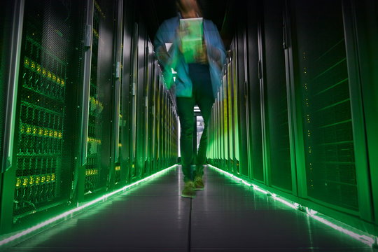 IT technician walking in dark, glowing server room