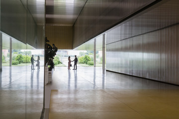 Silhouette businessman businesswoman handshaking in modern office corridor