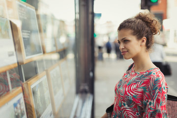 Young woman browsing real estate listings at urban storefront