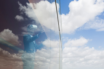 Businessman using virtual reality simulator glasses at window cloud reflection