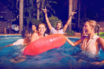 Portrait young friends playing in swimming pool at night
