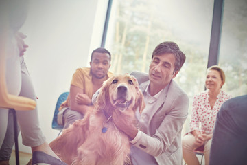 Man petting dog in group therapy session