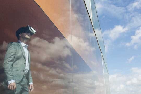 Businessman using virtual reality simulator glasses at modern window cloud reflection