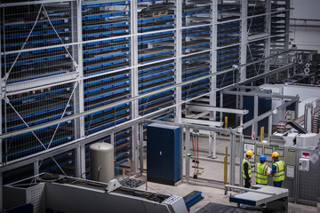 Supervisor and workers discussing information hanging on wall in factory