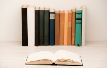 stack of books on wooden desk, with open book