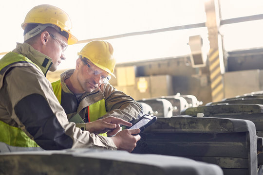Steelworkers using digital tablet in steel mill