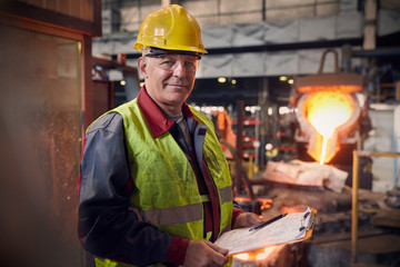 Portrait confident steelworker supervisor with clipboard in steel mill