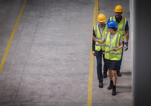 Female supervisor and male workers walking and talking in factory