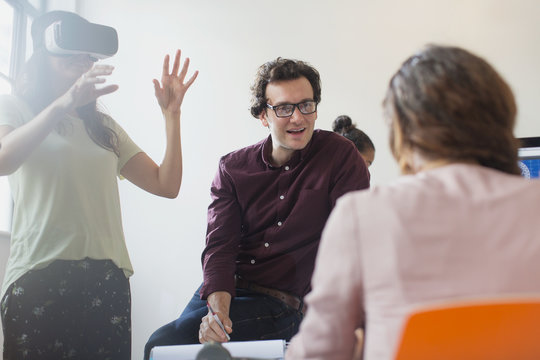 Computer programmers testing virtual reality simulator glasses in conference room meeting