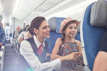 Female flight attendant helping girl on airplane