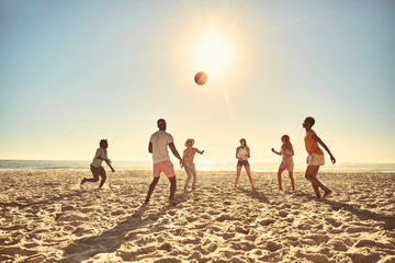 Young friends playing with beach ball on sunny summer beach